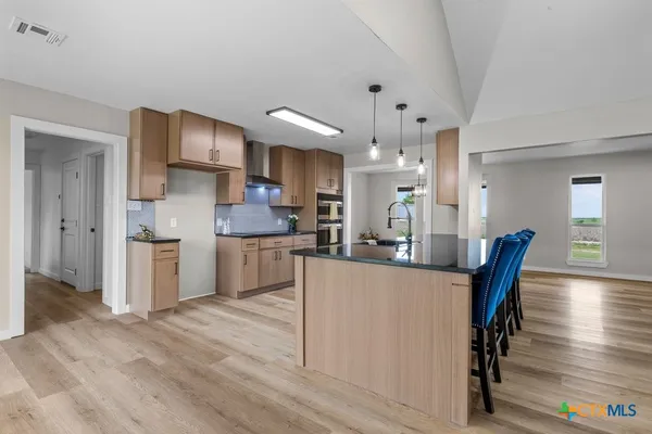 a kitchen with stainless steel appliances kitchen island granite countertop a table chairs in it and wooden floors