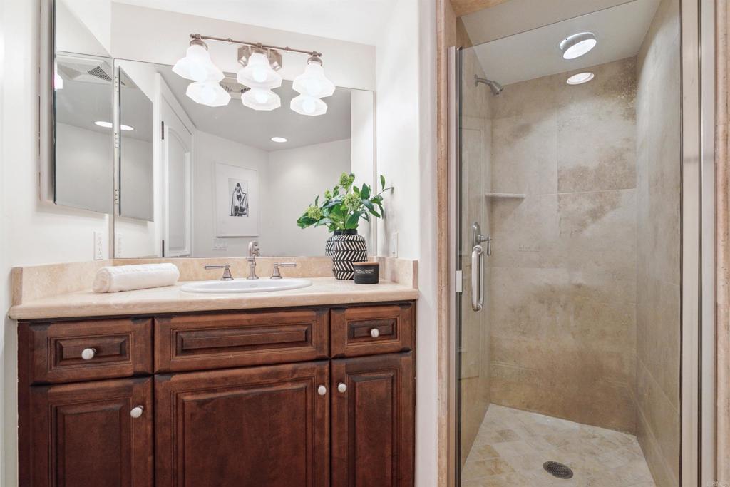 848 Prospect Street, Unit C La Jolla, CA 92037 - Photo 22 of 24 a bathroom with a granite countertop sink a mirror and a shower