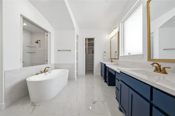 a spacious bathroom with a double vanity sink mirror and bathtub