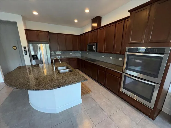 a kitchen with kitchen island granite countertop a stove a sink and a microwave