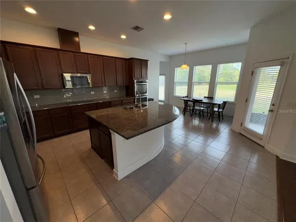 a kitchen with kitchen island granite countertop a sink a counter top space appliances and cabinets