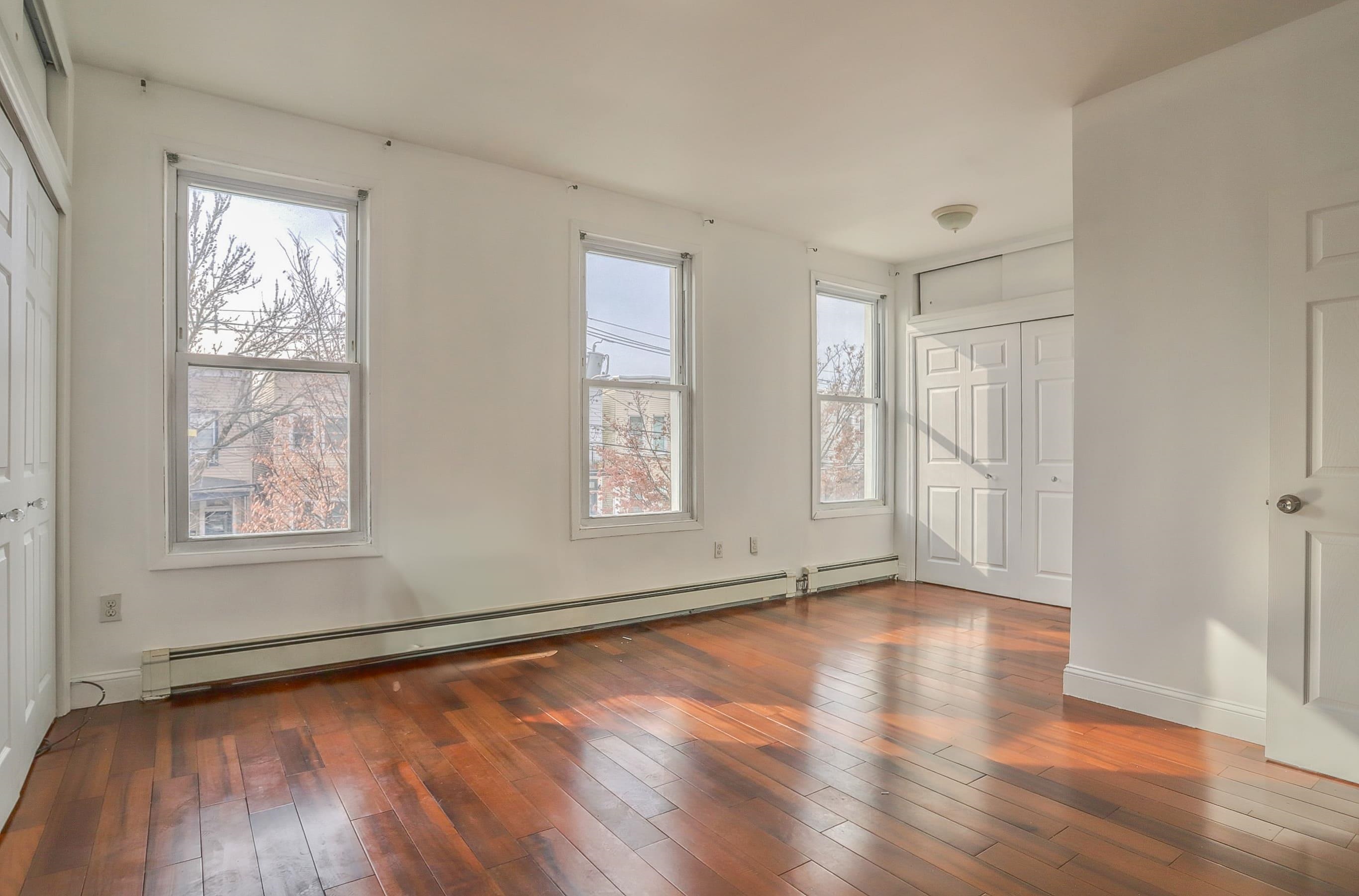 206 Dodd Street, Unit 2 Weehawken, NJ 07086 - Photo 15 of 20 an empty room with wooden floor and windows
