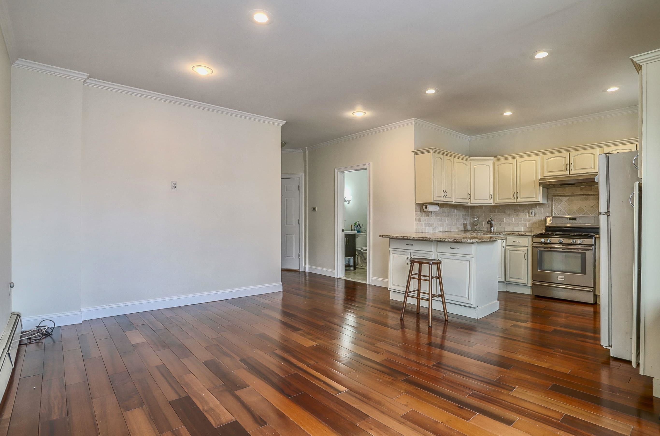 206 Dodd Street, Unit 2 Weehawken, NJ 07086 - Photo 3 of 20 a kitchen with a refrigerator and white cabinets with wooden floor