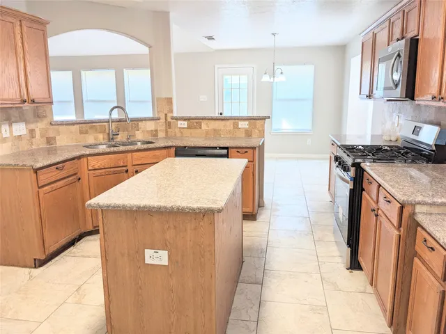 a kitchen with stainless steel appliances granite countertop a stove a sink and a refrigerator