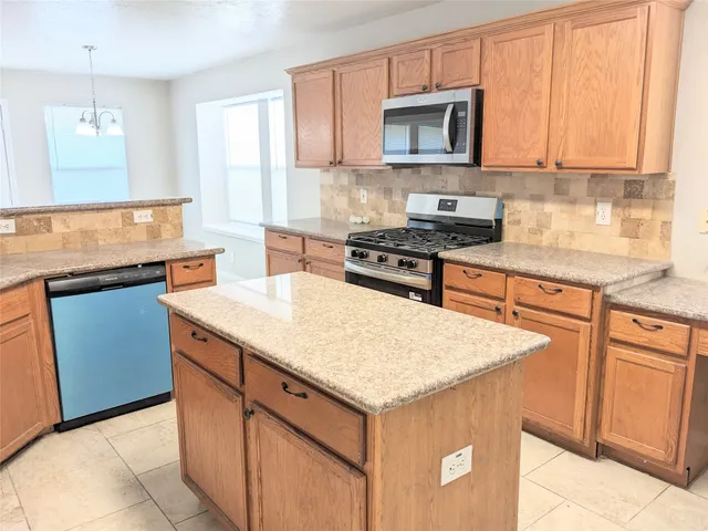 a kitchen with stainless steel appliances granite countertop wooden cabinets stove top oven and sink