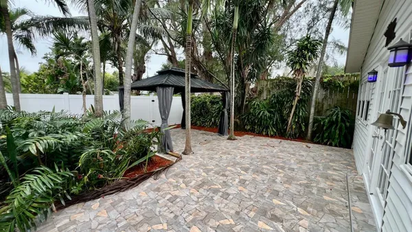 a view of a yard with plants and a barbeque