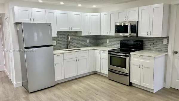 a kitchen with cabinets stainless steel appliances and sink