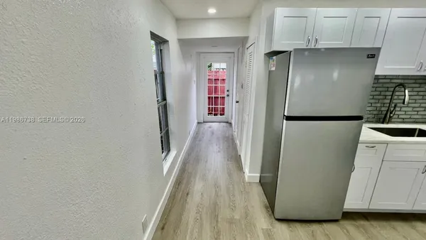 a view of a kitchen with refrigerator and wooden floor