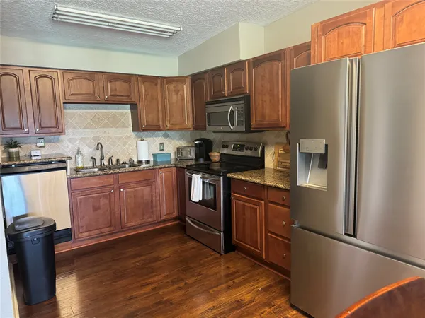 a kitchen with stainless steel appliances granite countertop a refrigerator stove a sink and dishwasher with wooden floor