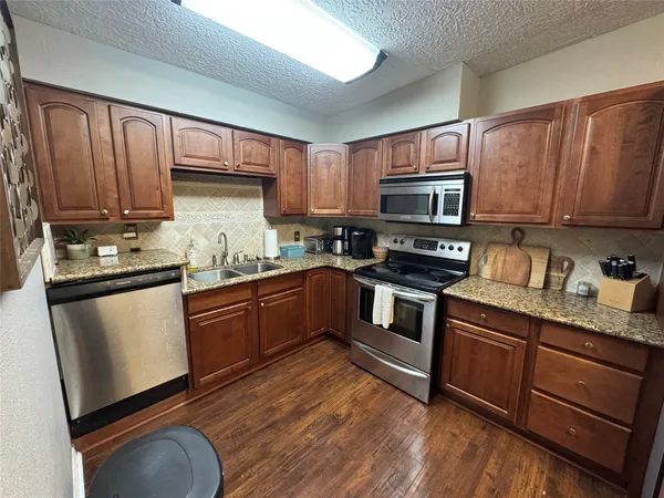 a kitchen with granite countertop wooden cabinets a stove a oven and a refrigerator