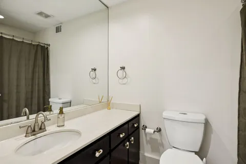 a bathroom with a sink toilet vanity and shower