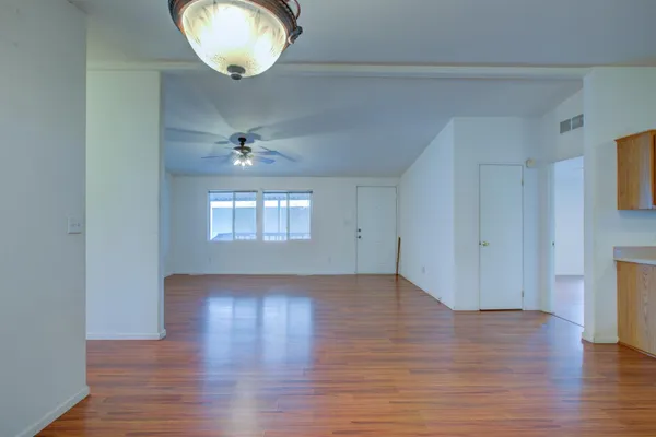 an empty room with wooden floor and windows
