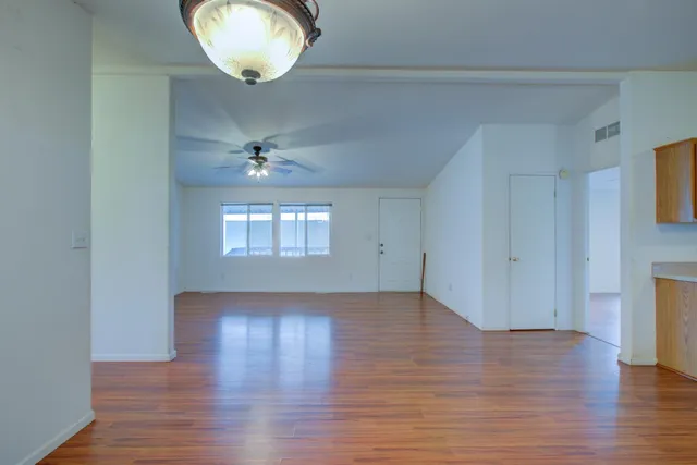 an empty room with wooden floor and windows