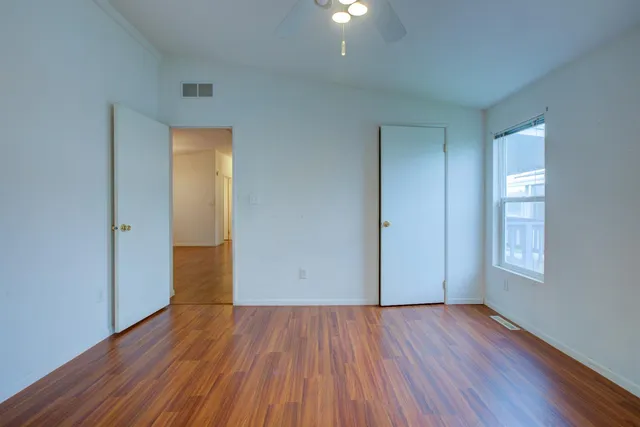 an empty room with wooden floor and windows