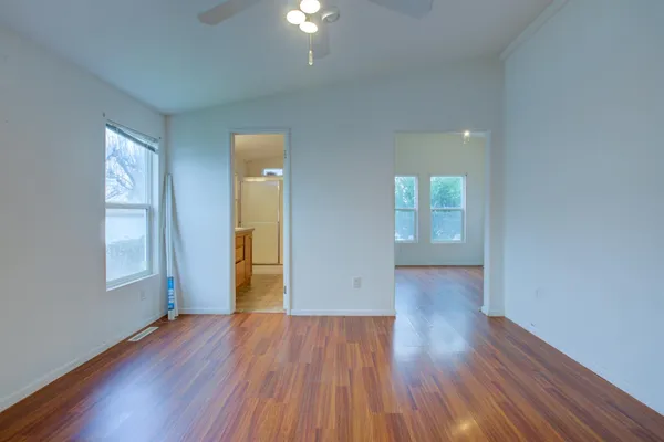 an empty room with wooden floor and windows