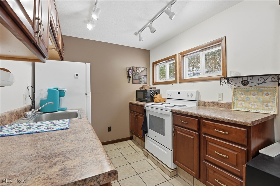 4254 Doral Road Southwest Carrollton, OH 44615 - Photo 26 of 46 Kitchen featuring white appliances, track lighting, and light tile patterned flooring