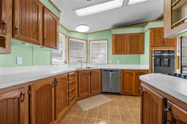 a kitchen with stainless steel appliances granite countertop wooden cabinets a sink and a large window
