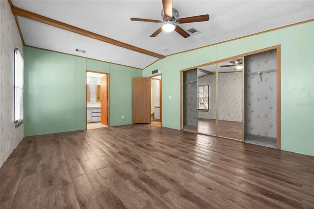 a view of an empty room with window and wooden floor