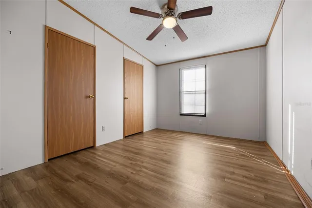 an empty room with wooden floor ceiling fan and windows