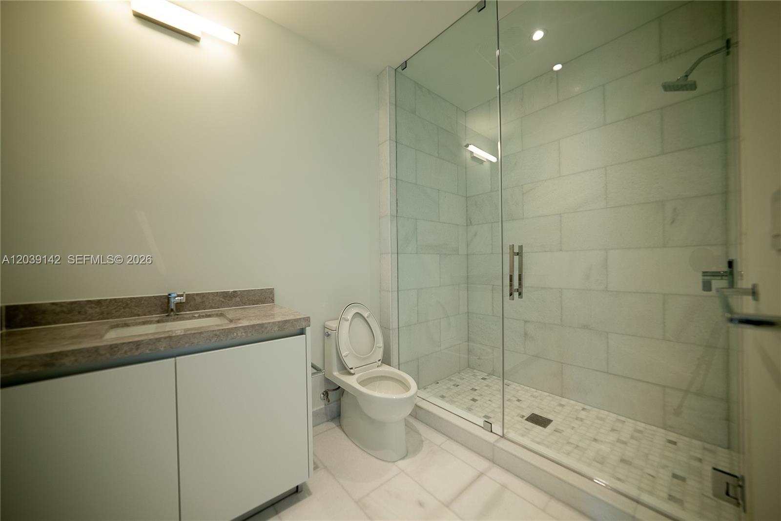 175 Southeast 25th Road, Unit 702 Miami, FL 33129 - Photo 28 of 30 a bathroom with a granite countertop sink a toilet and shower