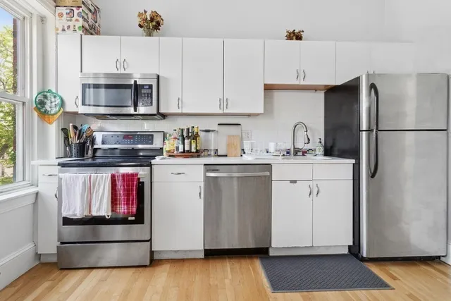 a kitchen with a sink stainless steel appliances and white cabinets