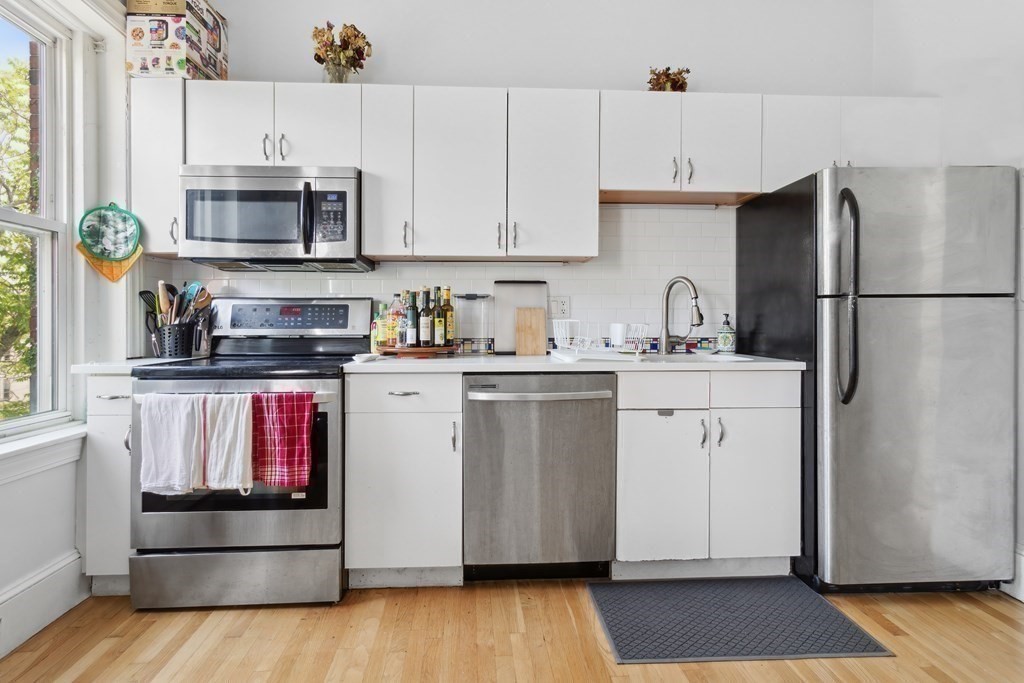 28 Beacon Street, Unit 3 Somerville, MA 02143 - Photo 5 of 11 a kitchen with a sink stainless steel appliances and white cabinets