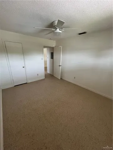 an empty room with a ceiling fan and window
