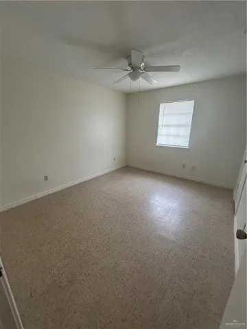 an empty room with a chandelier fan and windows