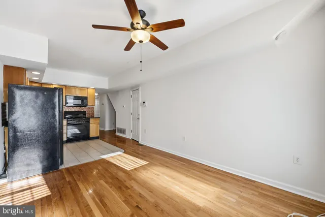 an empty room with wooden floor ceiling fan and windows