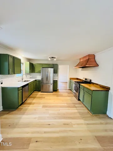 a kitchen with stainless steel appliances granite countertop a sink stove refrigerator and cabinets