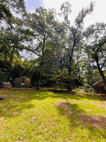 a view of a house with a big yard and large trees