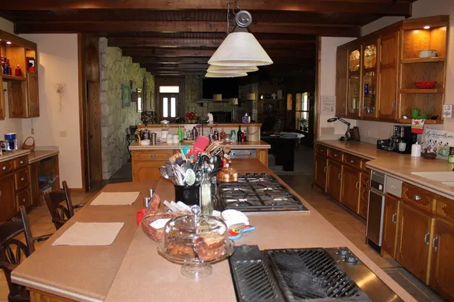 a kitchen with stainless steel appliances kitchen island granite countertop a stove a refrigerator a sink and dishwasher with wooden floor