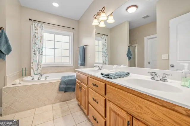 a spacious bathroom with a double vanity sink large mirror and a bathtub