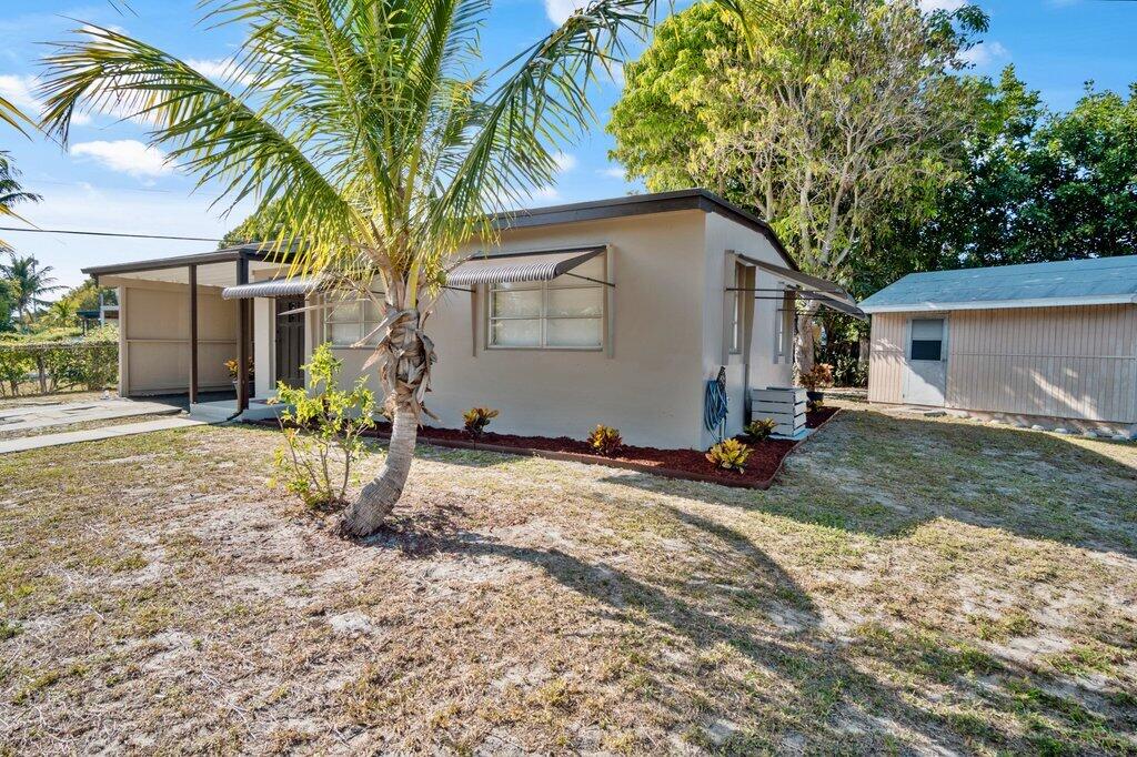 591 Oleander Road Lake Worth, FL 33462 - Photo 6 of 43 a backyard of a house with potted plants and large tree