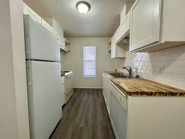 a kitchen with granite countertop a refrigerator a sink and dishwasher