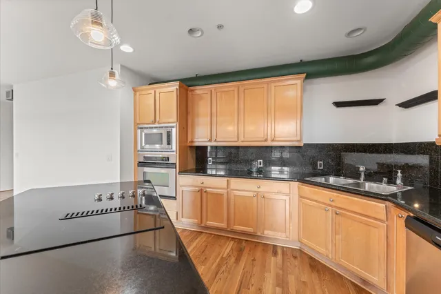 a kitchen with stainless steel appliances granite countertop a sink a stove and refrigerator