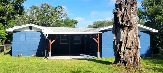a view of a wooden house with a large yard and large trees