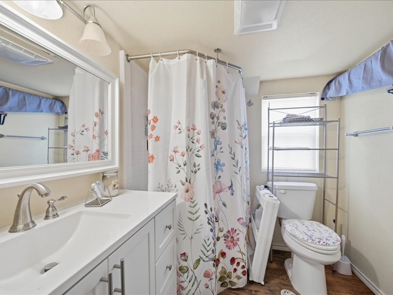 600 South Main Street Spavinaw, OK 74366 - Photo 28 of 42 White vanity with integrated sink, brushed nickel faucet, large framed mirror, and a shower with a curved rod