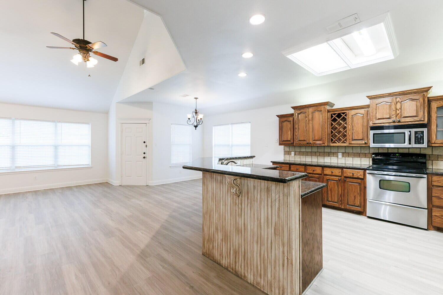 5908 95th Street Lubbock, TX 79424 - Photo 13 of 45 a kitchen with stainless steel appliances granite countertop a sink a stove a refrigerator cabinets and wooden floor