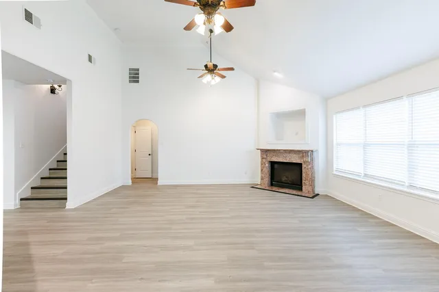 an empty room with windows and fireplace