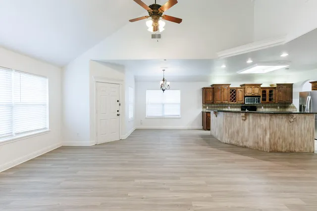 a view of kitchen and empty room with wooden floor