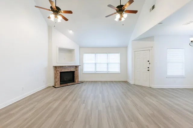 an empty room with windows and a ceiling fan