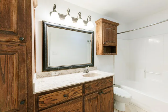 a bathroom with a granite countertop sink toilet and mirror