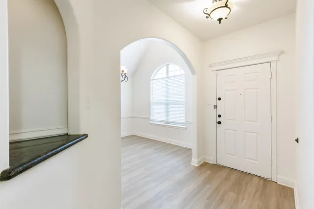 an empty room with wooden floor mirror and windows