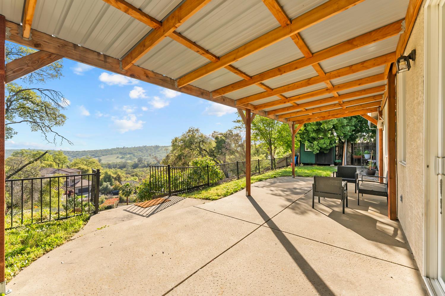 4285 Crazy Horse Road Cameron Park, CA 95682 - Photo 68 of 91 a view of a patio with a table and chairs under an umbrella next to a yard