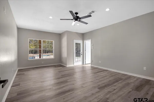 a view of an empty room with a window and wooden floor