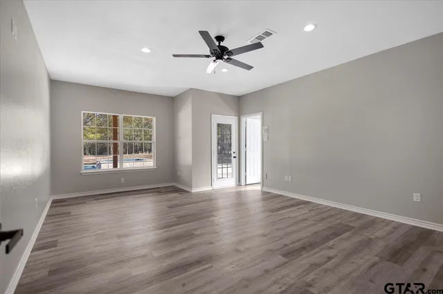 a view of an empty room with a window and wooden floor