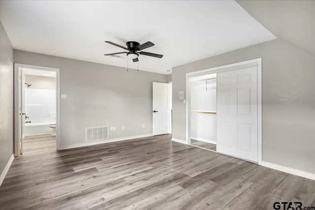 a view of empty room with wooden floor and ceiling fan