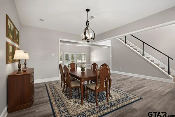 a dining room with wooden floor a chandelier a wooden table and chairs
