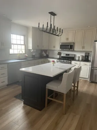 a kitchen with stainless steel appliances a sink a stove a refrigerator cabinets and a dining table with wooden floor